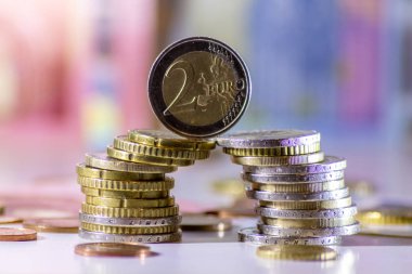 Arka plandaki Avrupa sikkeleri yığını ve banka notları, Avro ve Avrupa, Avrupa ticaret ve mali ticaretinin yanı sıra tasarruf, mali başarı ve kredi yönetimi ile uluslararası finansmanı gösteriyor