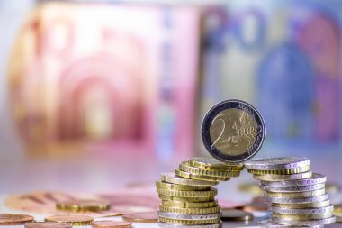 Arka plandaki Avrupa sikkeleri yığını ve banka notları, Avro ve Avrupa, Avrupa ticaret ve mali ticaretinin yanı sıra tasarruf, mali başarı ve kredi yönetimi ile uluslararası finansmanı gösteriyor