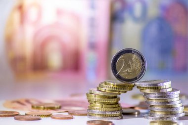 Arka plandaki Avrupa sikkeleri yığını ve banka notları, Avro ve Avrupa, Avrupa ticaret ve mali ticaretinin yanı sıra tasarruf, mali başarı ve kredi yönetimi ile uluslararası finansmanı gösteriyor