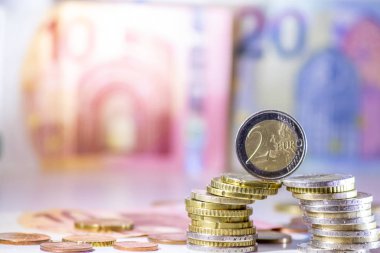 Arka plandaki Avrupa sikkeleri yığını ve banka notları, Avro ve Avrupa, Avrupa ticaret ve mali ticaretinin yanı sıra tasarruf, mali başarı ve kredi yönetimi ile uluslararası finansmanı gösteriyor