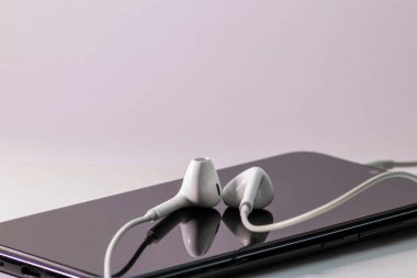 Video ve ses akışı için mobil akıllı telefon ya da dijital yerlilerin ses ve video oynaması için kulaklıklarda beyaz kulaklık ile birlikte ses ve video akışları dinlemek için mobil cihaz