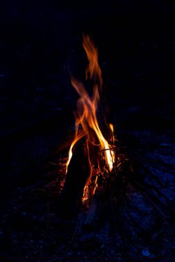 Shiny burning fire in the dark shows the romantic side of a campfire or bonfire, fire safety and the need of a fire insurance as well as survival adventures outdoor with the children and the family