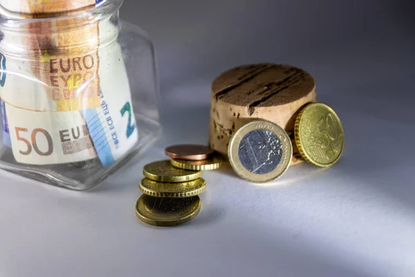 Glass piggy bank with european bank notes and euro coins show savings for travelling, holidays, private investment and cash as well as poverty and low salary and low wages of poor people in europe
