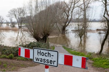 fence on river coast in Germany indicating high tide and flood water with flooded coastline after broken dike