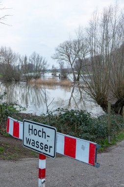fence on river coast in Germany indicating high tide and flood water with flooded coastline after broken dike