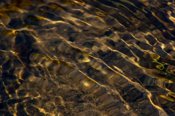 Silky ripples in water of a crystal clear water creek as idyllic natural background with high angle view shows zen meditation and little waves in a healthy mountain spring with a clear floating stream