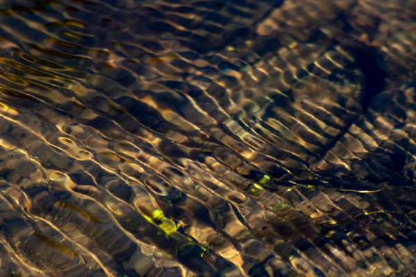 Silky ripples in water of a crystal clear water creek as idyllic natural background with high angle view shows zen meditation and little waves in a healthy mountain spring with a clear floating stream