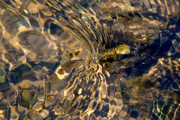 Silky ripples in water of a crystal clear water creek as idyllic natural background with high angle view shows zen meditation and little waves in a healthy mountain spring with a clear floating stream