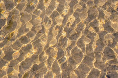 Kristal berrak bir su deresinin suyundaki ipeksi dalgalar, yüksek açılı doğal arka plan, temiz yüzen bir dereyle sağlıklı bir dağ pınarındaki zen meditasyonunu ve küçük dalgaları gösterir.