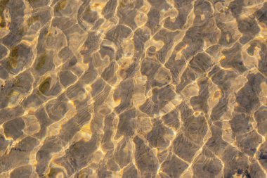 Kristal berrak bir su deresinin suyundaki ipeksi dalgalar, yüksek açılı doğal arka plan, temiz yüzen bir dereyle sağlıklı bir dağ pınarındaki zen meditasyonunu ve küçük dalgaları gösterir.