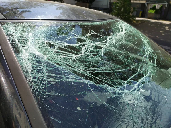 Broken glass of the broken windshield after a heavy car accident ruined the windscreen and caused an injury that shattered and cracked the glass to show the need for car insurance damage insurance