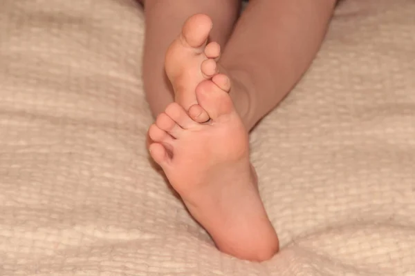Children's feet on a blanket. Feet on the bed.