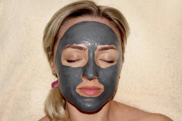 Girl with a cleansing mask for the face. Spa procedures. Mask based on activated carbon.