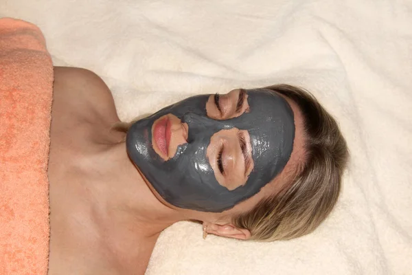 Girl with a cleansing mask for the face. Spa procedures. Mask based on activated carbon.