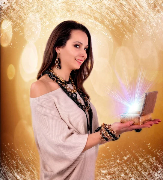 Kvinnan håller i hennes händer en låda som ljusstrålar på abstrakt bakgrund — Stockfoto