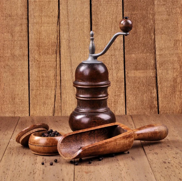 Mill for grinding pepper with a spatula on a wooden background