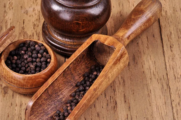 Mill for grinding pepper with a spatula on a wooden background