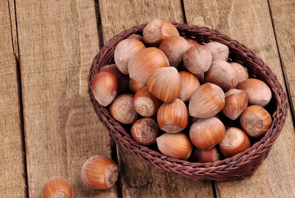 Lískové ořechy v proutěném koši na detail dřevěné pozadí — Stock fotografie