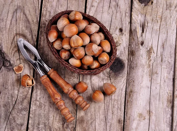 Hazelnuts in basket with walnut on wooden background — Stock Photo, Image