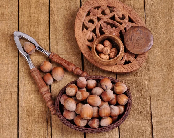 Hazelnuts in basket with walnut on wooden background — Stock Photo, Image