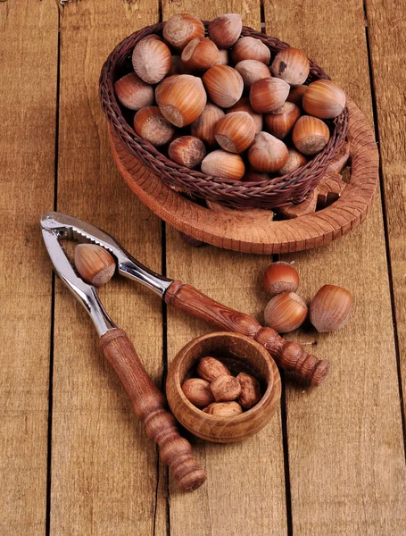 Lískové ořechy v koši s ořech na dřevěné pozadí — Stock fotografie