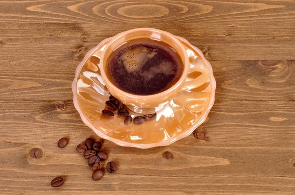 Café dans une tasse orange sur un fond en bois — Photo