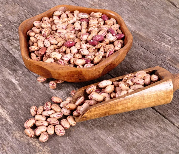 Beans in a wooden bowl on an old wooden background — Stock Photo, Image