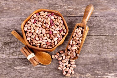 Eski bir ahşap zemin üzerine ahşap bir kasede renkli fasulye