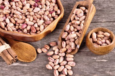 Eski bir ahşap zemin üzerine ahşap bir kasede renkli fasulye