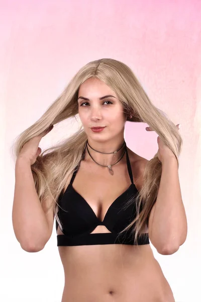 Beautiful girl with long blond hair in a black bra on an abstrac — Stock Photo, Image