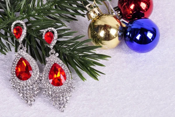 Earrings with red stones on a branch of a Christmas tree with a — Stock Photo, Image