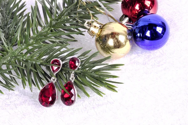 Earrings with red stones on a branch of a Christmas tree with a — Stock Photo, Image