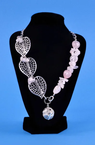 Collana in argento con pietre di quarzo rosa su uno stand nero su un bl — Foto Stock