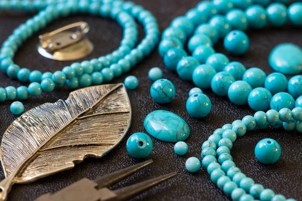 Turquoise  stones, beads and  tools for making jewelry.  Needlework.