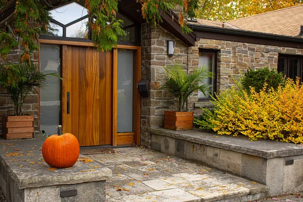 Большая тыква стоит у входных дверей перед модным домом. Сезон украшения на Хэллоуин в США и Канаде . — стоковое фото