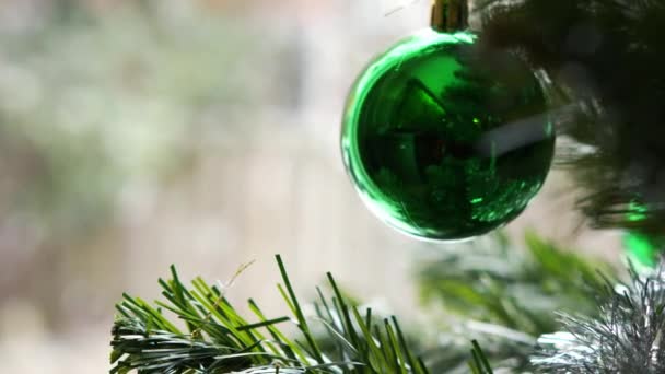 Bulanık kar yağışının dışarıda görülebildiği pencerede asılı olan yeşil Noel ağacı oyuncağı. Noel ve yeni yıl havası, ev konforu ve aile yeni yıl tatili. — Stok video