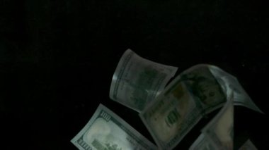 4K Loopable 'daki siyah arka planda düşen Amerikan doları banknotları. 4K 'da yüksek kalitede düşen dolar banknotları. Görüntü Döngüsel