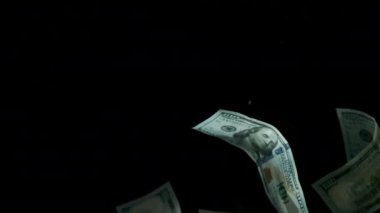 4K Loopable 'daki siyah arka planda düşen Amerikan doları banknotları. 4K 'da yüksek kalitede düşen dolar banknotları. Görüntü Döngüsel