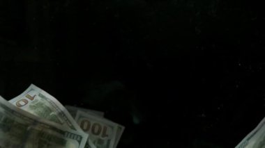 4K Loopable 'daki siyah arka planda düşen Amerikan doları banknotları. 4K 'da yüksek kalitede düşen dolar banknotları. Görüntü Döngüsel