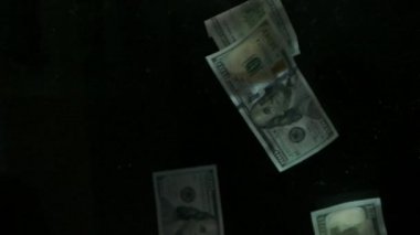 4K Loopable 'daki siyah arka planda düşen Amerikan doları banknotları. 4K 'da yüksek kalitede düşen dolar banknotları. Görüntü Döngüsel