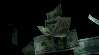 Düşen Amerikan doları banknotları siyah arka planda.