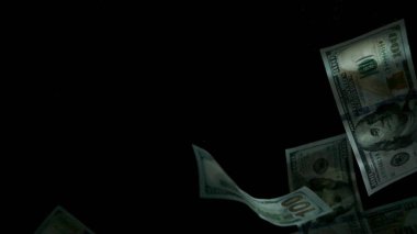 Düşen Amerikan doları banknotları siyah arka planda.