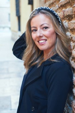 Kız sokak duvarına yaslanıyor.