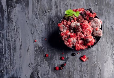 Siyah arka planda siyah bir kasede donmuş bir meyvenin en üst görüntüsü. Koruma kavramı