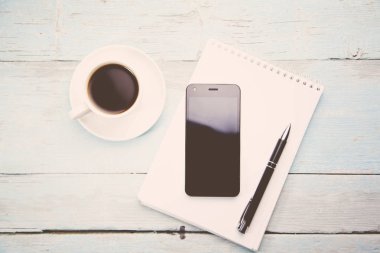 telefon ve üstünde defter kalem 