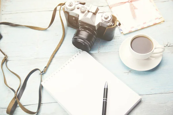 Ноутбук, ручка, камера и кофе на столе — стоковое фото