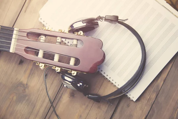 Białe słuchawki na gitarze i notatnika — Zdjęcie stockowe