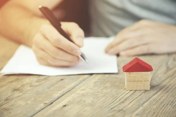 Uomo penna a mano e casa — Foto Stock