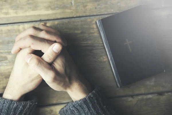 Молодий чоловік молиться і Біблія на столі — стокове фото
