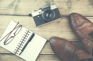 Seyahat kavramı - ayakkabı, not defteri, kamera, ahşap masa üzerinde gözlük